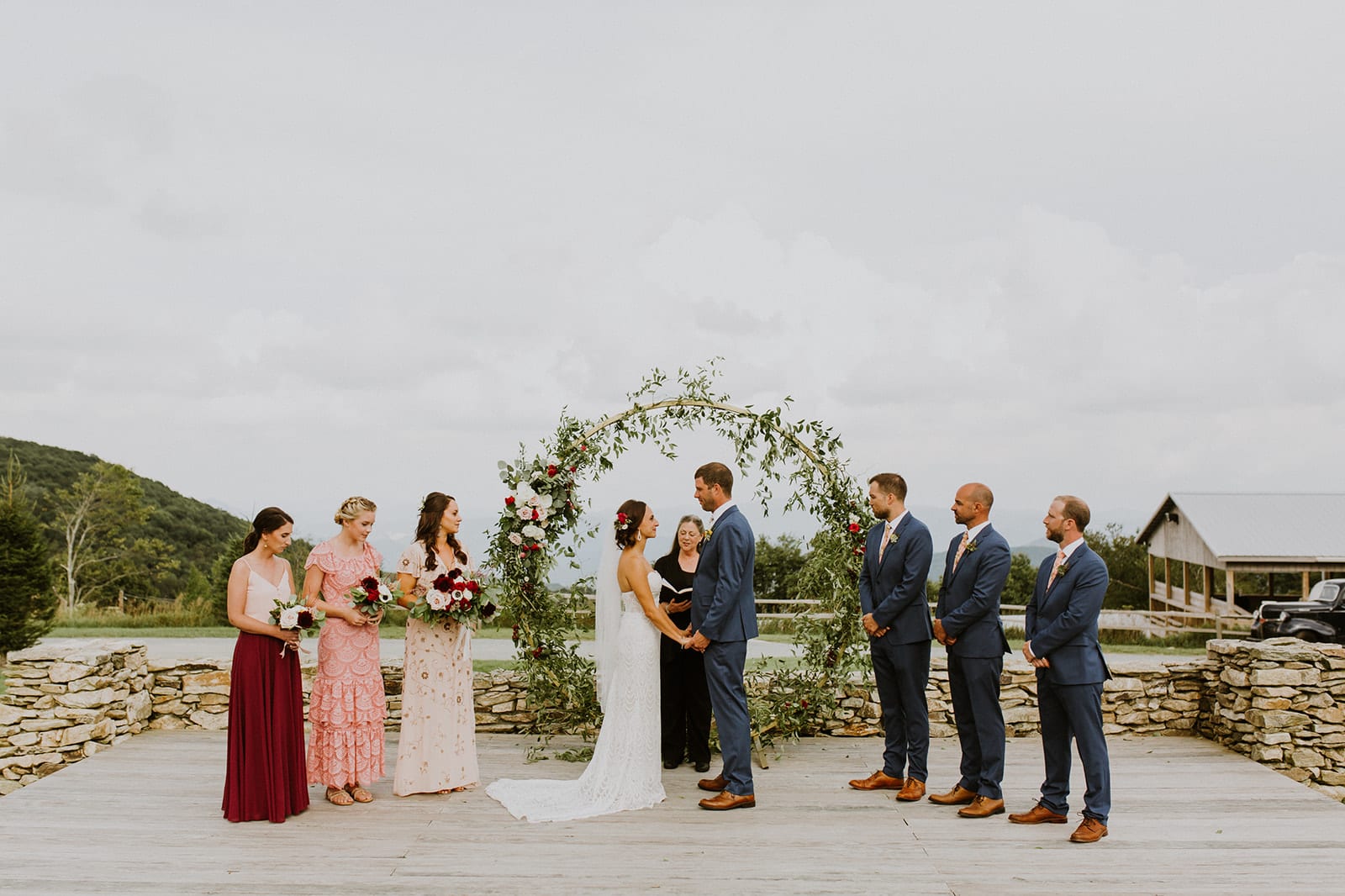 An intimate wedding ceremony in front of the blue ridge mountains at overlook barn, with a circle arbor adorned in lush florals.