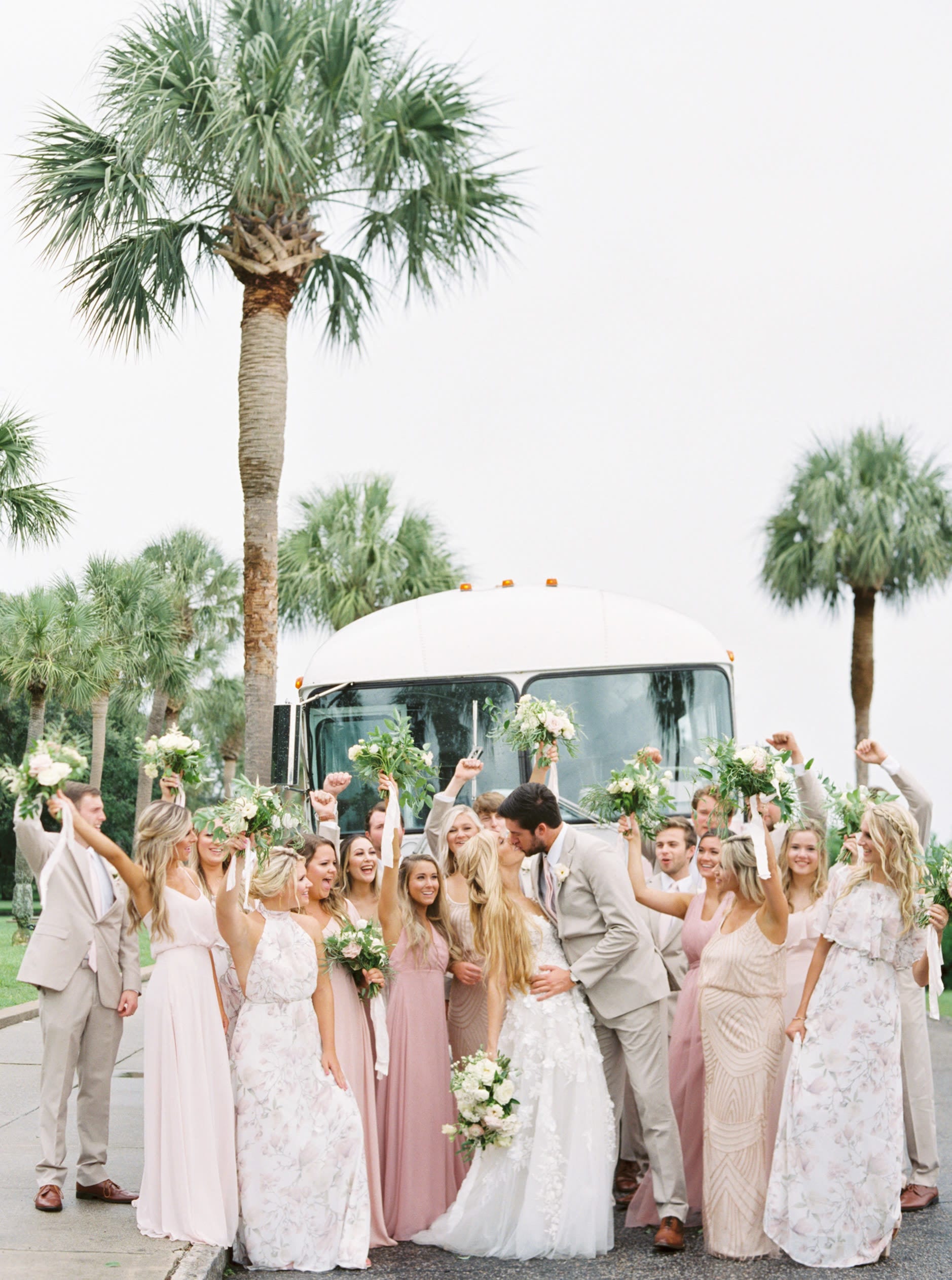 Bridal party standing in front of a vintage pink bus on their way to a luxury charleston destination wedding.